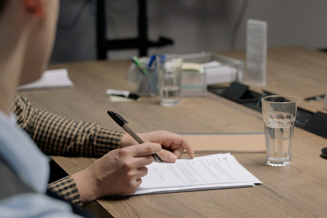 Person reviewing printed notes and a laptop screen at an office desk